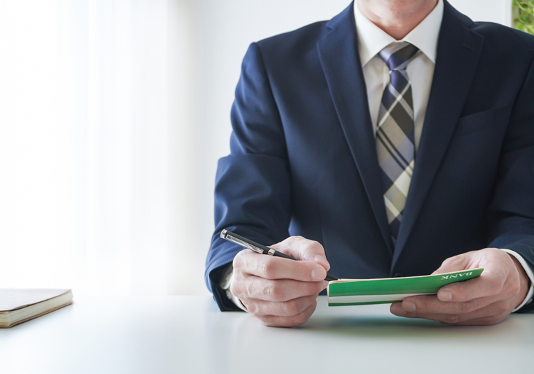 貯金通帳を持つスーツ姿の男性