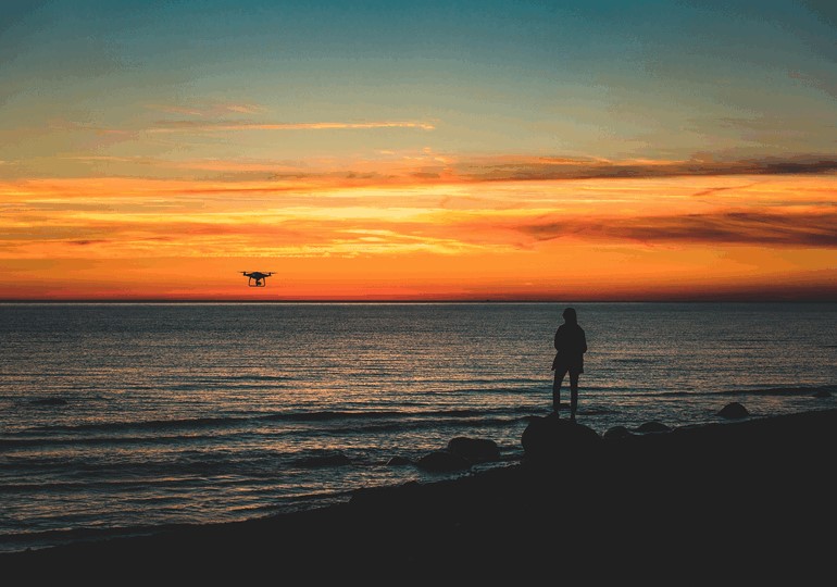 浜辺でドローンを飛ばして遊ぶ少年