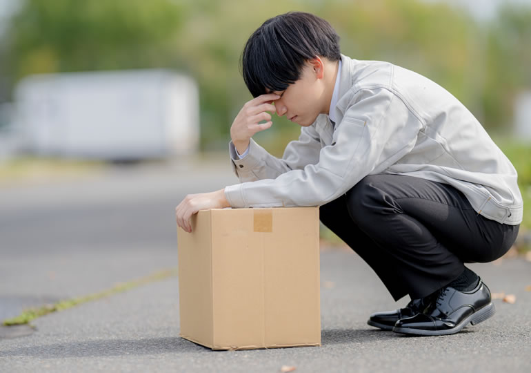 遺骨の入った箱をもって疲れた男性