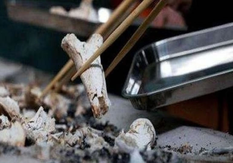 火葬後の遺骨を箸で収骨している遺族