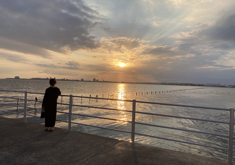浜辺から夕陽を見つめる女性のシルエット