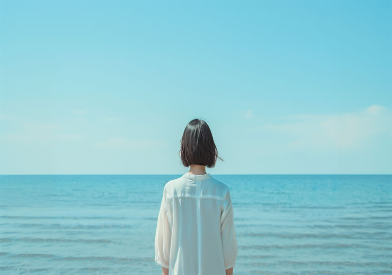 海洋散骨した海を浜辺から見つめる女性の後ろ姿