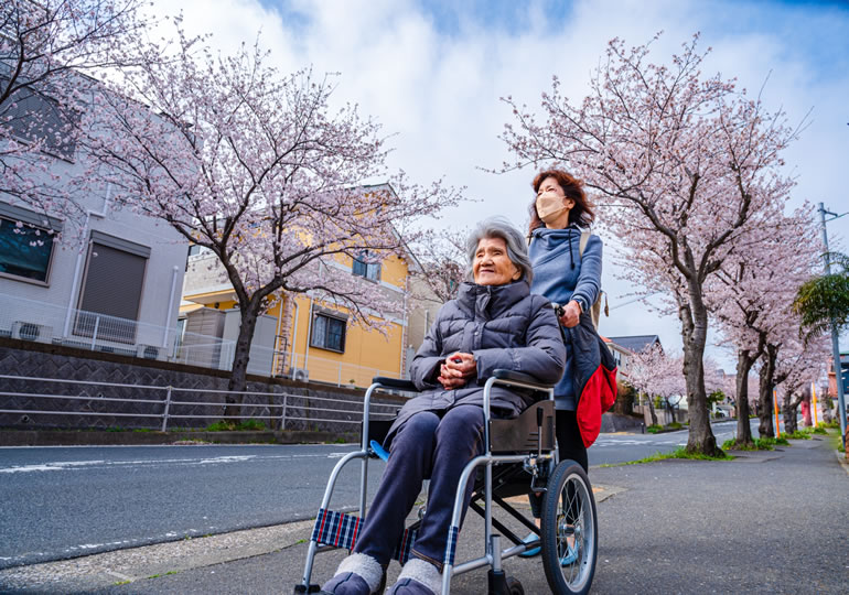 車椅子の老人を支援する女性