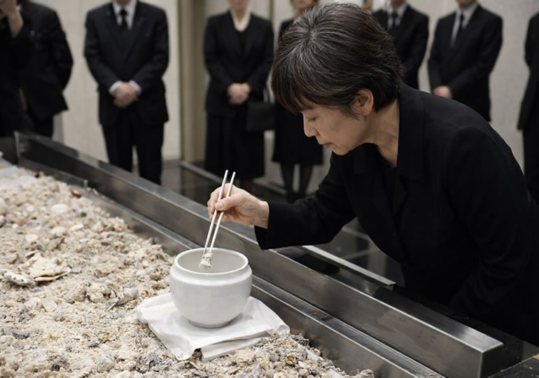 焼骨を収骨する高齢女性