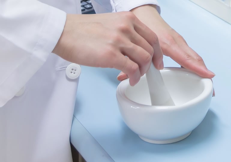 乳鉢で遺骨をパウダーにする女性