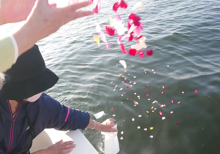 船の上から海洋散骨をする家族