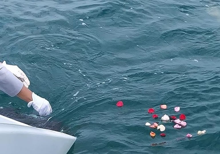 船上から海洋散骨の為に献花する画像