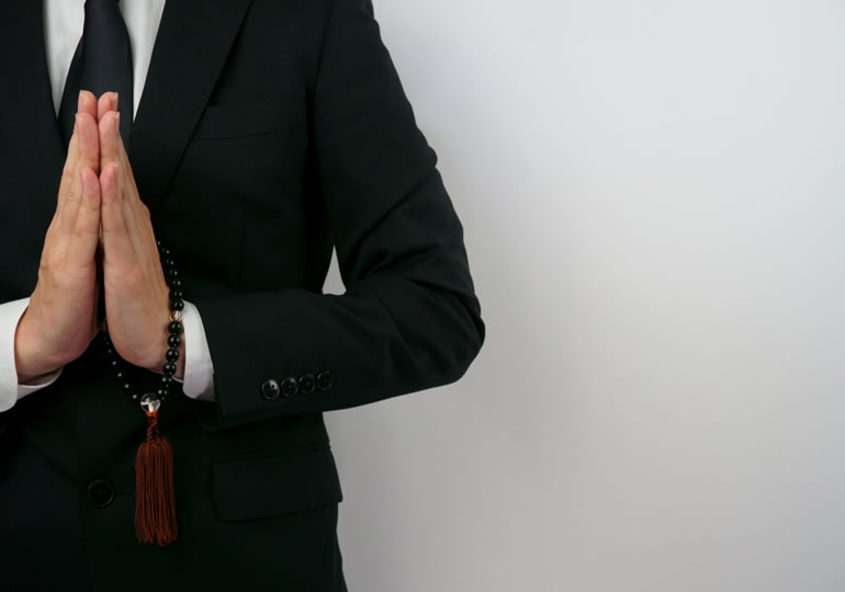 喪服で合掌する男性