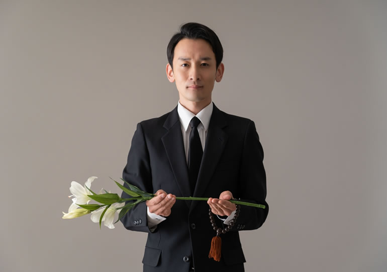 喪服で菊の花を持つ男性